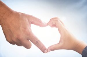 Die Hände von Vater und Kind formen ein Herz, sie sind Superhelden im Kampf gegen Krebs