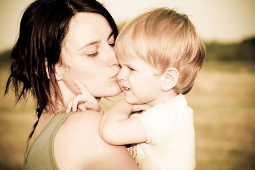 Mutter schreit nicht, küsst Kind auf dem Arm auf die Wange