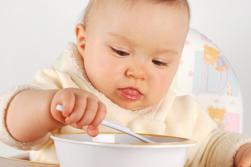 Die ersten Lebensmittel - Baby isst mit Löffel