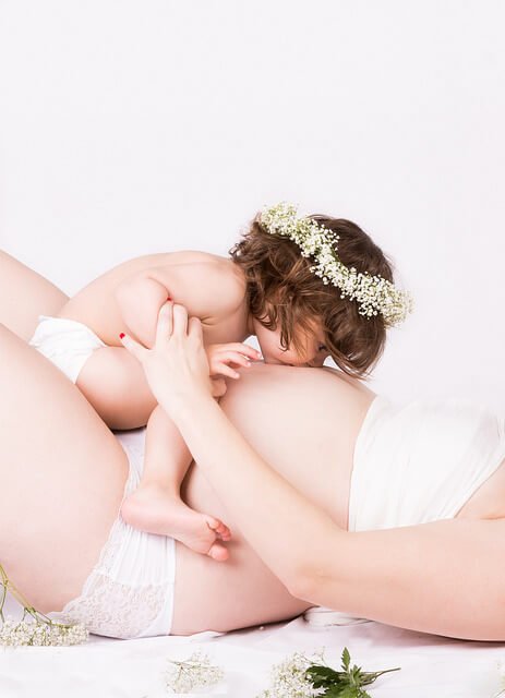 Kind küsst schwangeren Bauch für Pränatale Stimulation