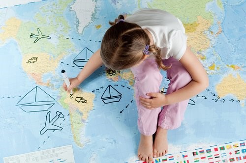 Reisen und andere Kulturen - Mädchen zeichnet auf Weltkarte