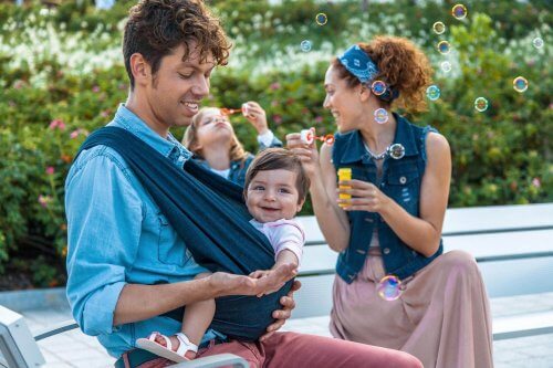 Vater und Mutter mit Kind in Babytrage