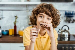 Kind isst Schokolade, um die intellektuelle Leistung zu stärken