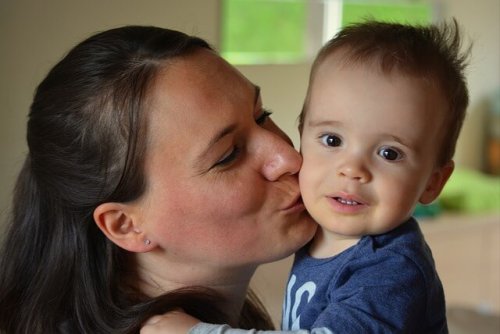 Die Mutter küsst ihren Sohn auf die Wange, um ihm Liebe entgegen zu bringen.