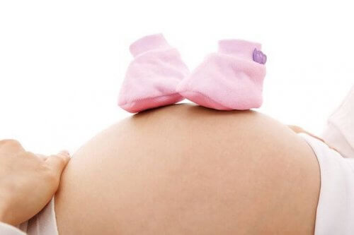 Bauch einer Schwangeren mit zwei Babyschuhen