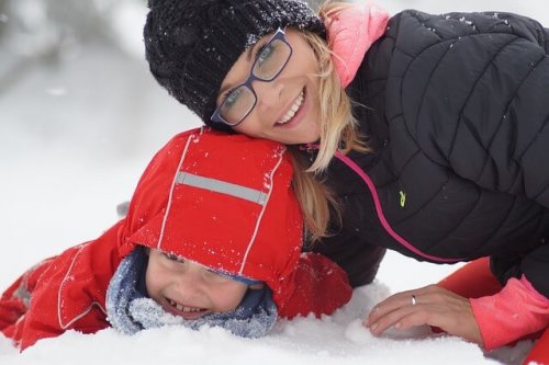 Mutter und Kind lachen im Schnee