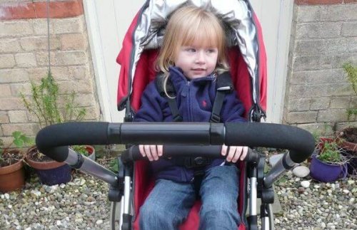 Kleines Mädchen sitzt in Kinderwagen.