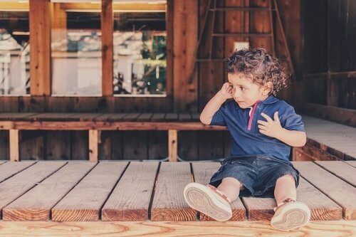 Kleiner Junge sitzt weinend auf einem Holzsteg.