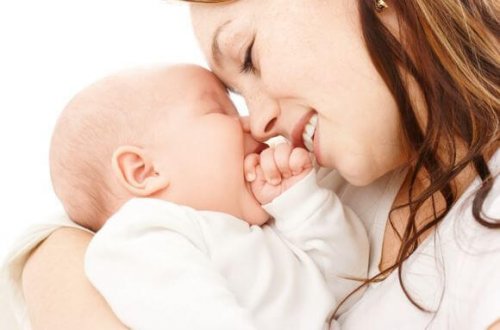 Mutter hält Baby im Arm und beide lachen.