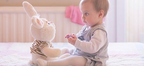 Baby spielt mit Plüschhase.