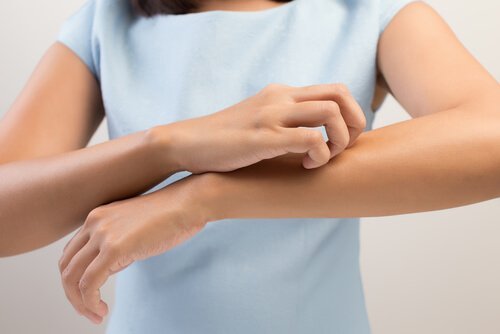 Kribbeln im Körper - Frau kratzt sich am Arm