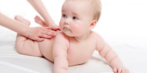 Mutter massiert Baby und stimuliert die Sinne.