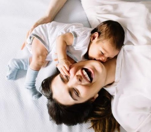 Mutter und Baby spielen lachend zusammen.