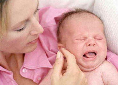 Mutter tröstet weinendes Baby während Stillkrise.