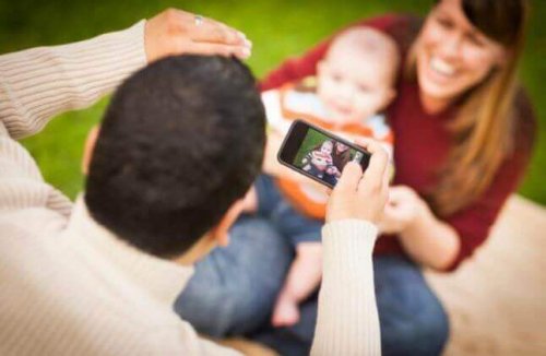 Vater macht ein Handybild von seinem Baby.
