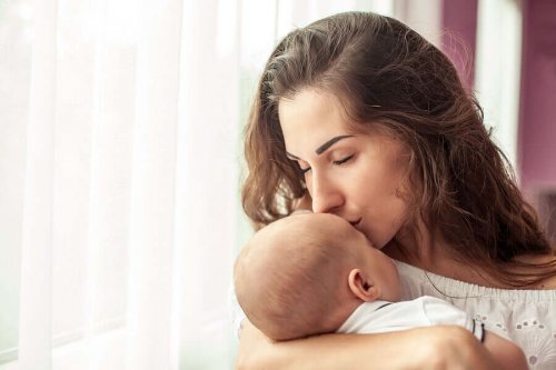 Wochenbett: Mutter küsst Baby am Fenster