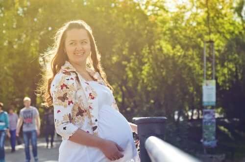 Schwangere Frau lacht in die Kamera