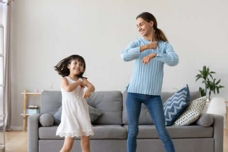 Kinderbetreuung: Mädchen und Kinderfrau tanzen vor dem Sofa