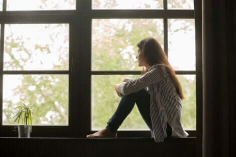 Mädchen sitzt am Fenster und blickt hinaus